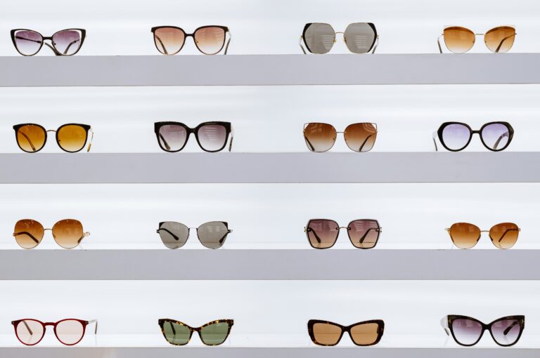 A display of various eyewear frames showing a retail comparison of Specsavers vs Vision Express vs Glasses Direct.