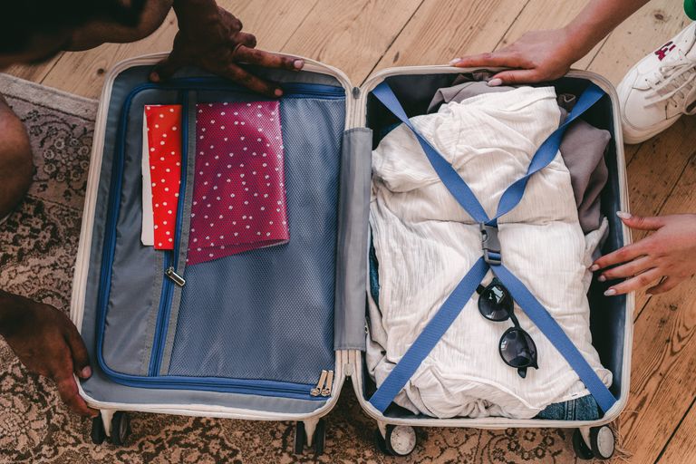 An open suitcase being packed for a holiday with clothes and a pair of sunglasses, showcasing essential prime day glasses accessories.
