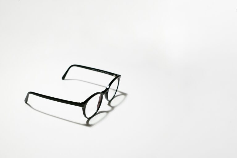 A pair of black-rimmed spectacles on a plain white surface, illustrating how long a glasses prescription is valid in the UK.