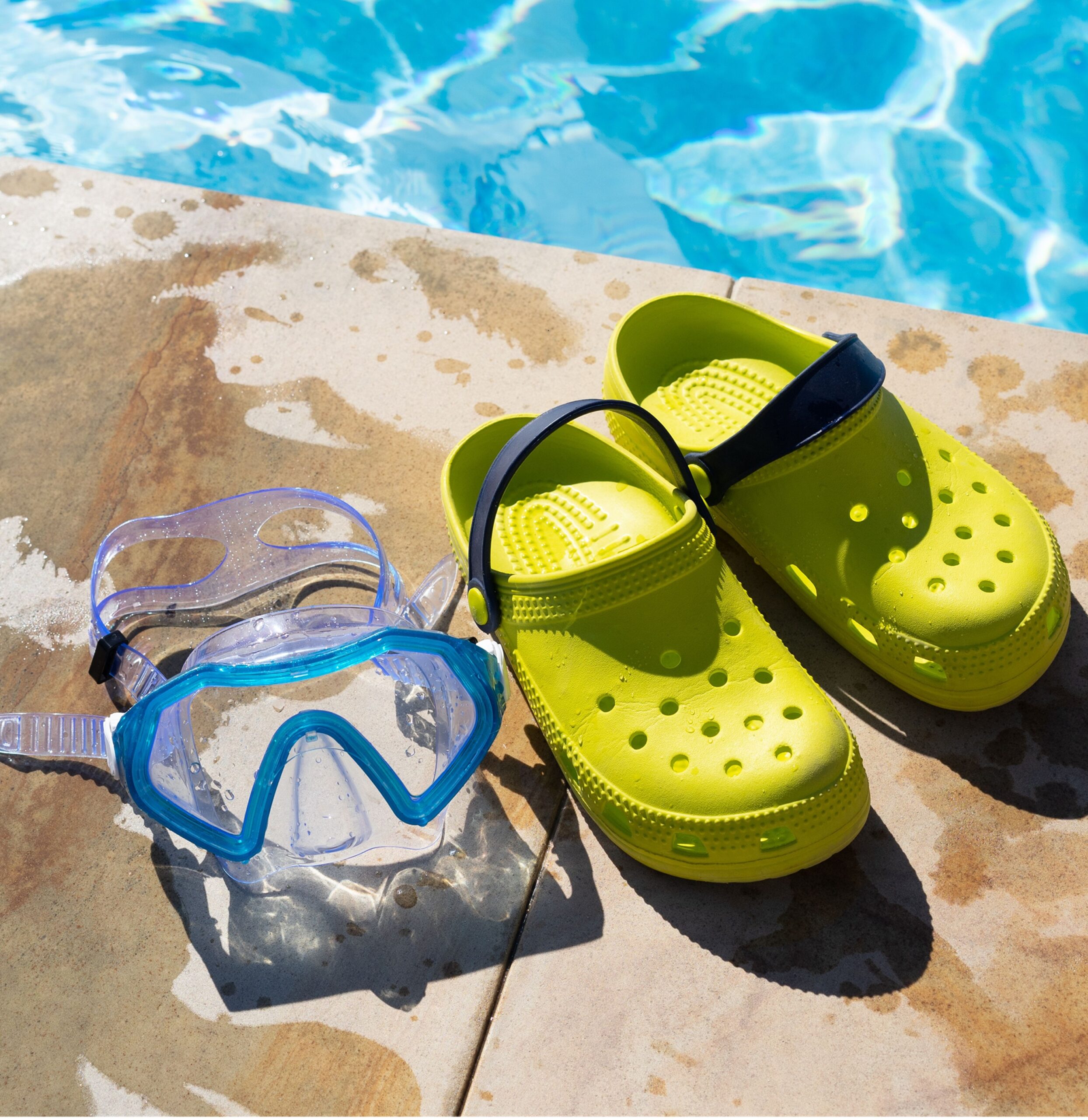 Bright green shoes and swimming goggles by a pool, showcasing essential accessories for prime day kids glasses.
