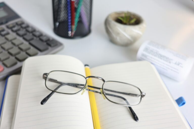 Glasses resting on a notebook next to a calculator, illustrating checking eligibility for Universal Credit free glasses