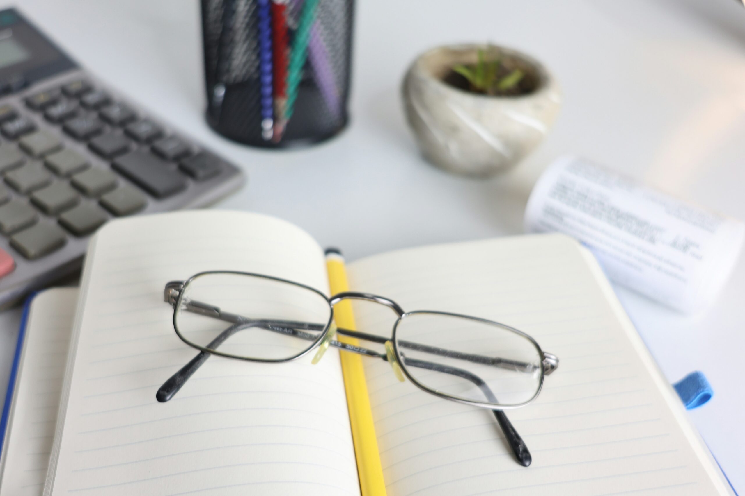 Glasses resting on a notebook next to a calculator, illustrating checking eligibility for Universal Credit free glasses