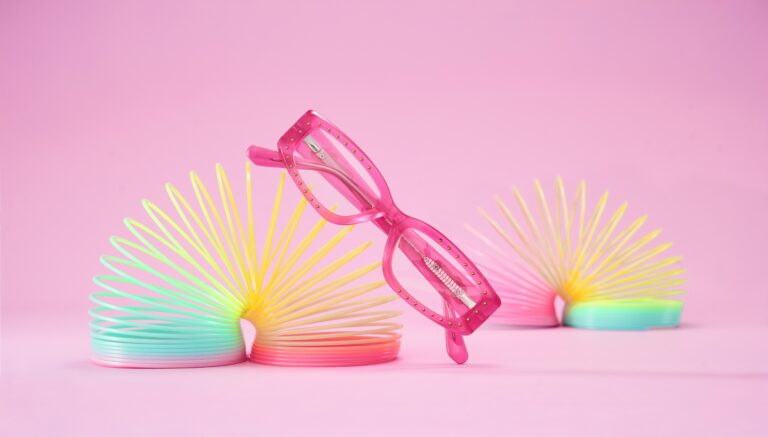 Pink children's glasses resting on colourful slinky toys, illustrating our Stellest lenses parent's guide